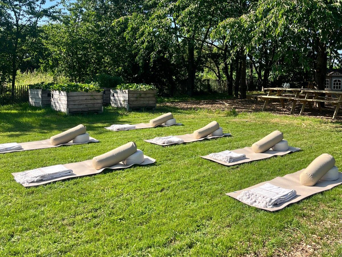 Yogamatten met bolsters klaargelegd in het gras van de boomgaard